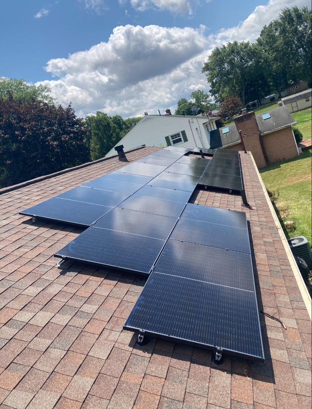 Solar panels on a residential shingle roof beneath a blue sky